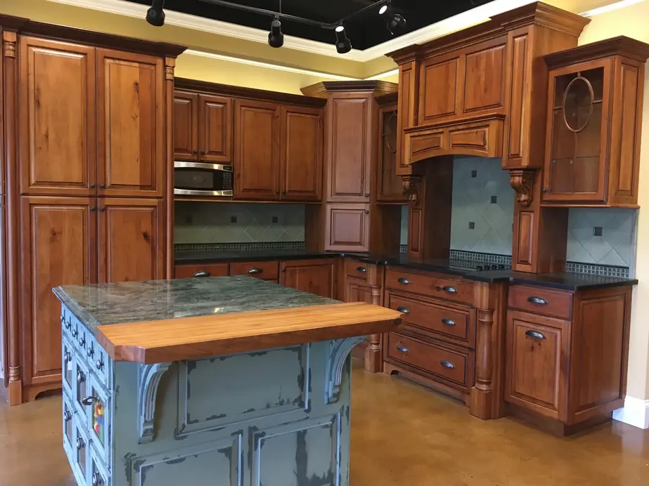 Showroom display kitchen in knotty alder with glass-front uppers, a hood surround and a painted island