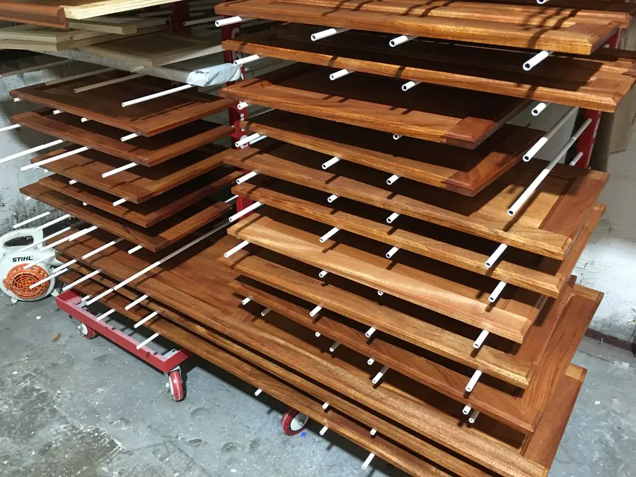 Rolling drying rack loaded with freshly finished cabinet doors in the shop
